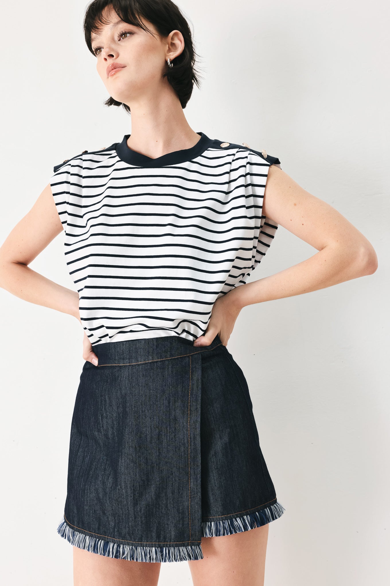 Woman wearing a dark denim skort featuring front flap, fray edge and back zipper closure | FREEMARKET