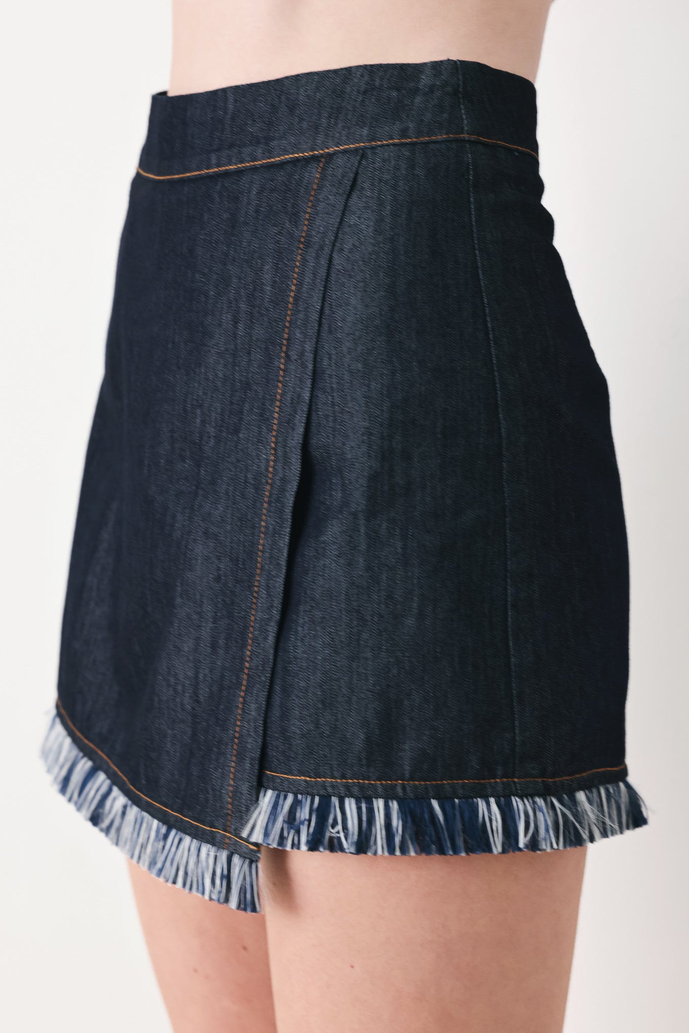 Woman wearing a dark denim skort featuring front flap, fray edge and back zipper closure | FREEMARKET