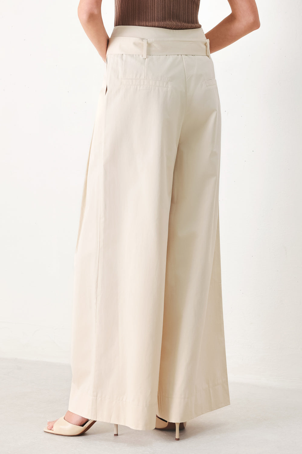Woman wearing beige wide-leg pants with self belt, front closure and pockets | FREEMARKET | Flying Tomato