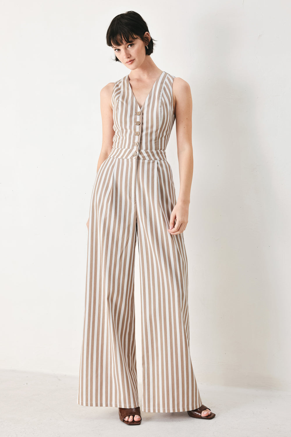 Woman wearing a striped woven jumpsuit featuring V neckline, sleeveless, front button/zipper closure and wide leg | FREEMARKET
