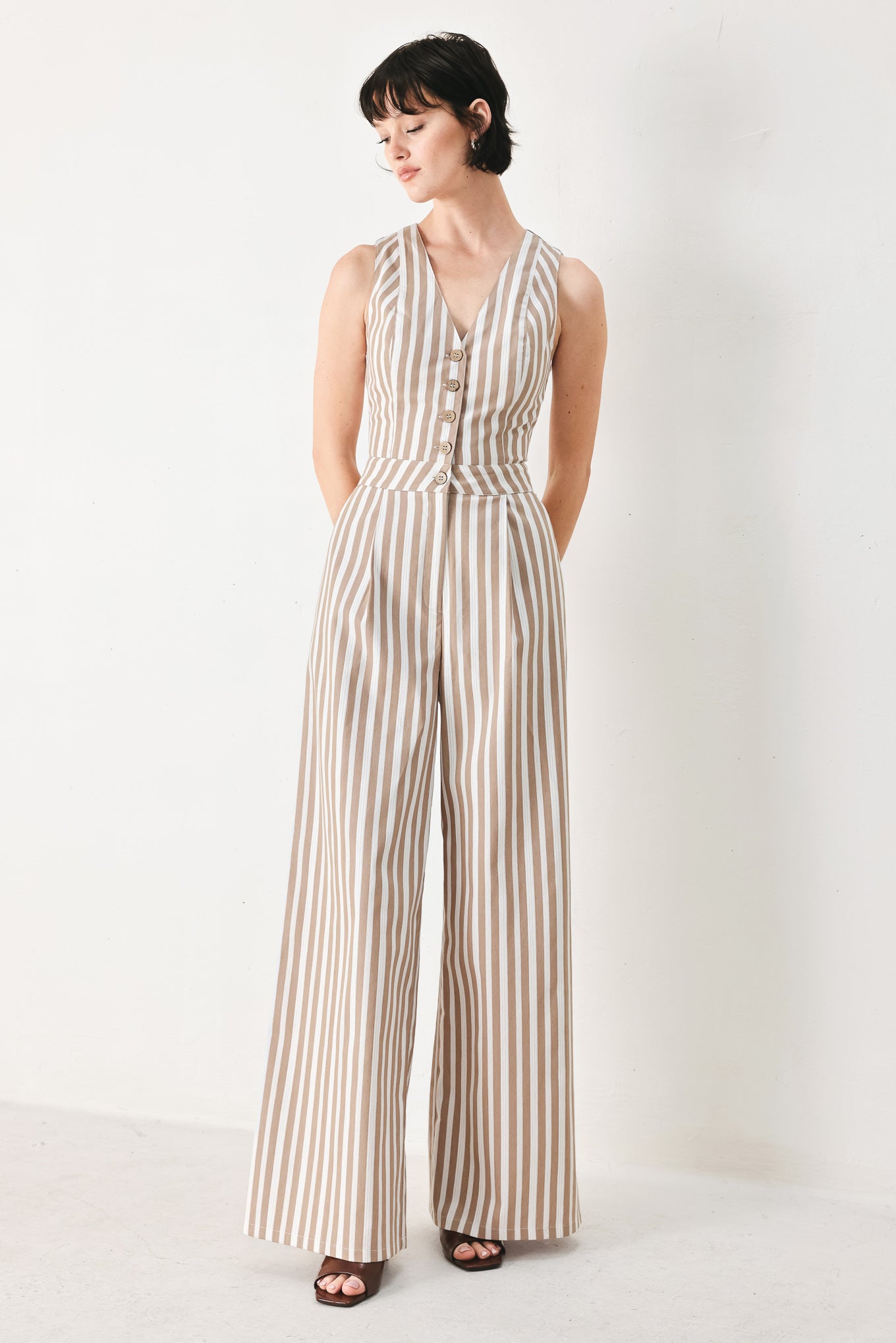 Woman wearing a striped woven jumpsuit featuring V neckline, sleeveless, front button/zipper closure and wide leg | FREEMARKET