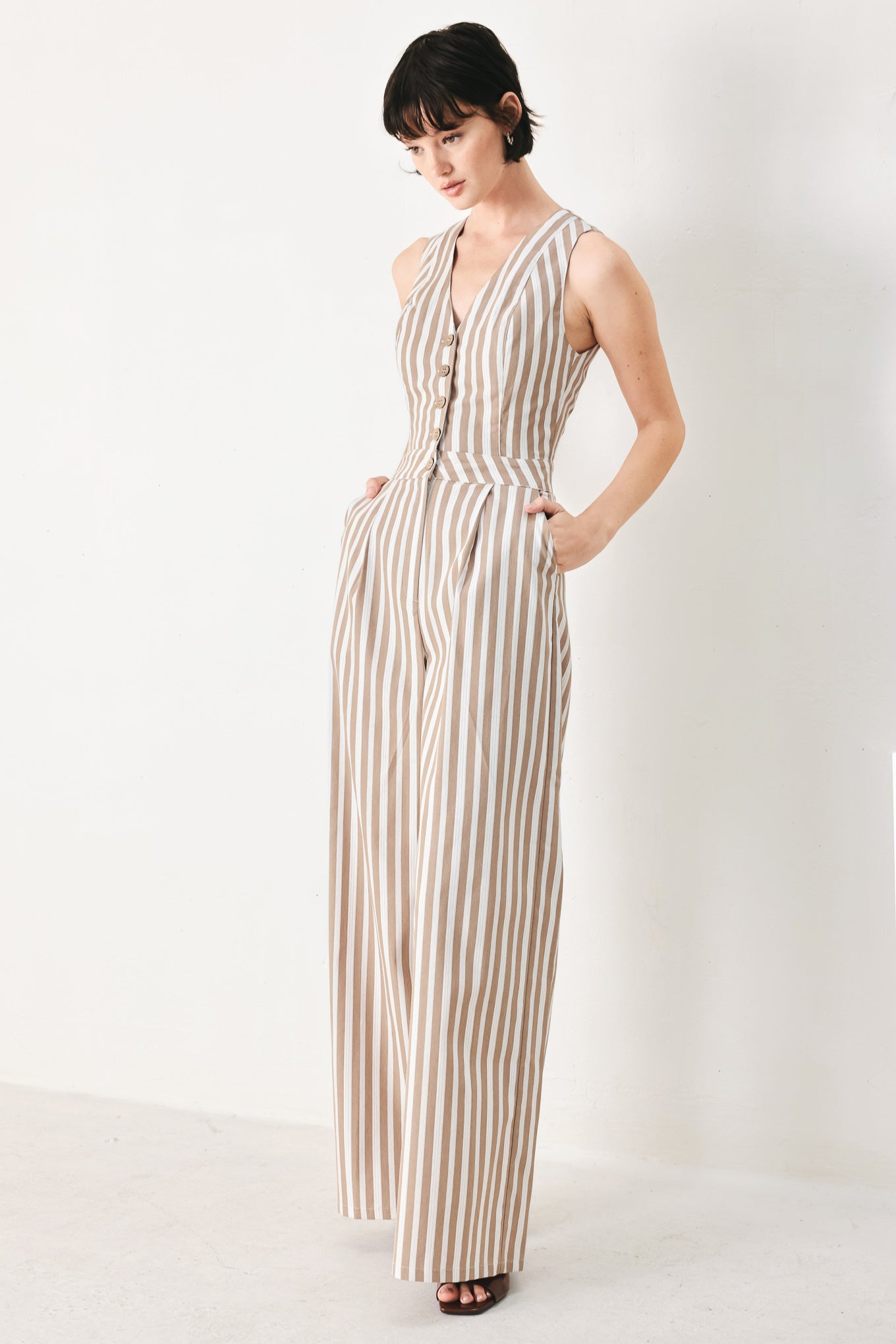 Woman wearing a striped woven jumpsuit featuring V neckline, sleeveless, front button/zipper closure and wide leg | FREEMARKET