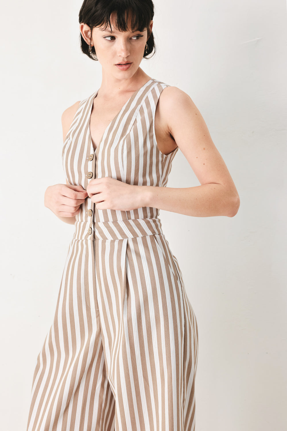 Woman wearing a striped woven jumpsuit featuring V neckline, sleeveless, front button/zipper closure and wide leg | FREEMARKET