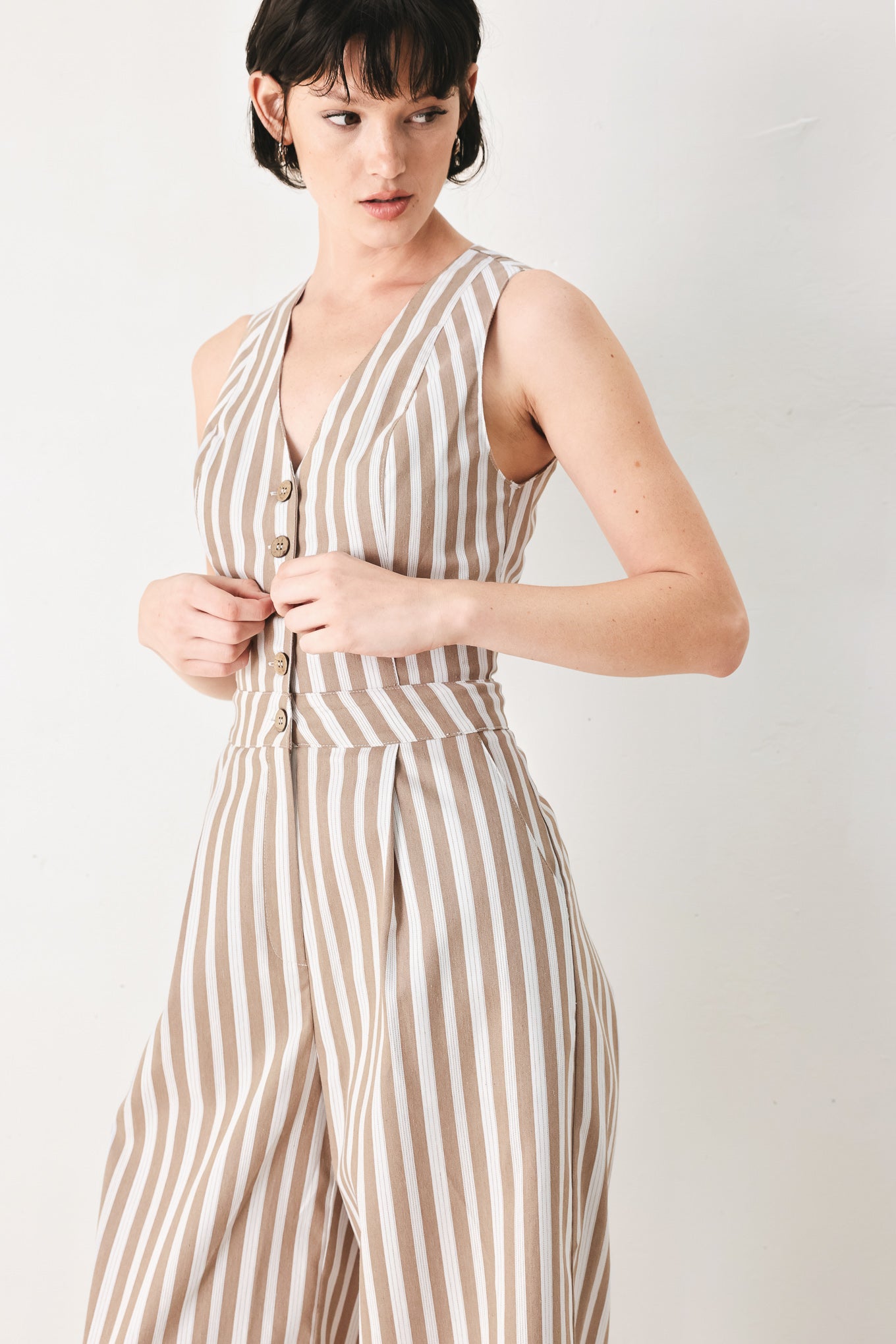 Woman wearing a striped woven jumpsuit featuring V neckline, sleeveless, front button/zipper closure and wide leg | FREEMARKET