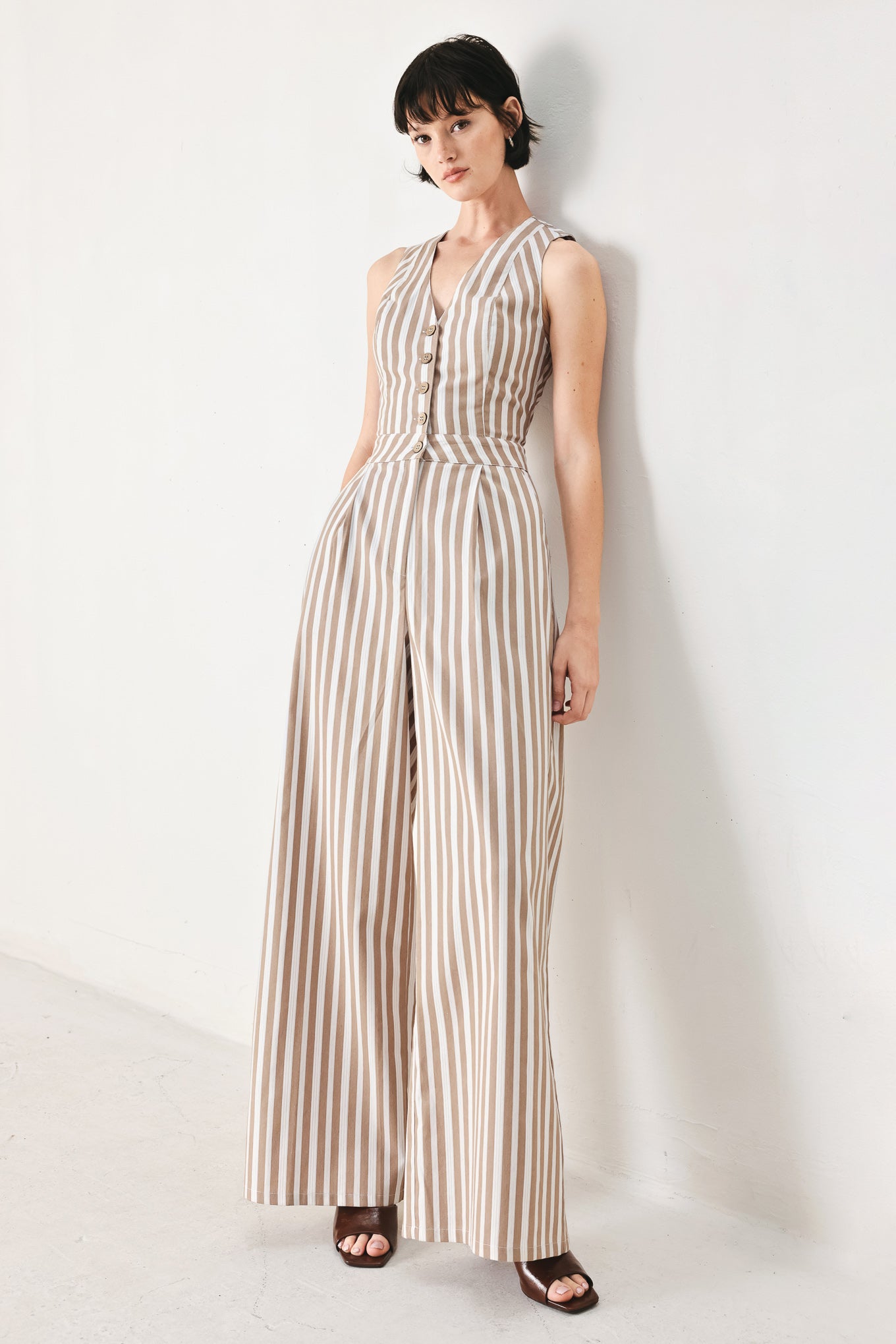 Woman wearing a striped woven jumpsuit featuring V neckline, sleeveless, front button/zipper closure and wide leg | FREEMARKET