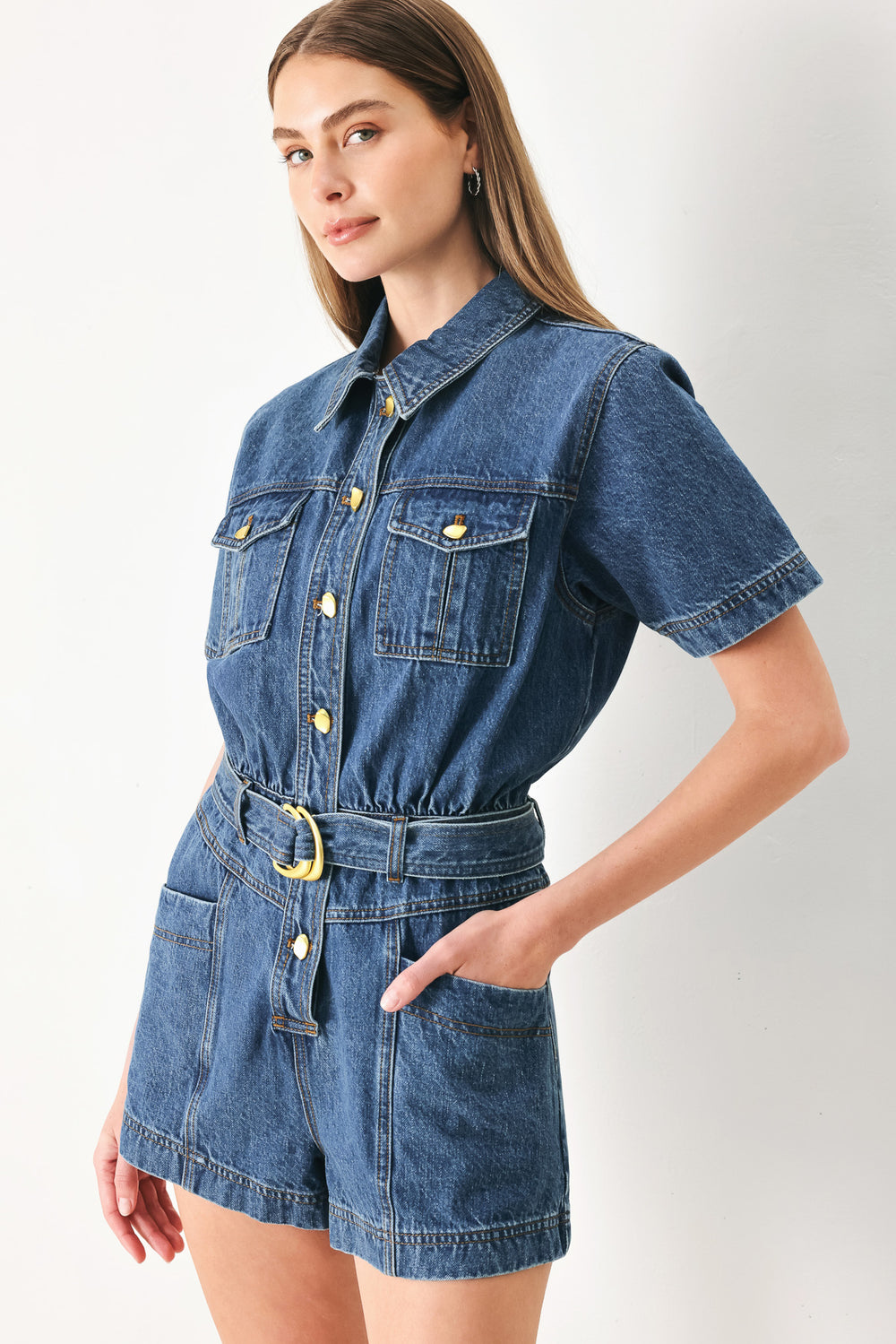 Woman wearing a denim romper featuring collar, button down closure, short sleeve, pockets and belt | FFREEMARKET | Flying Tomato