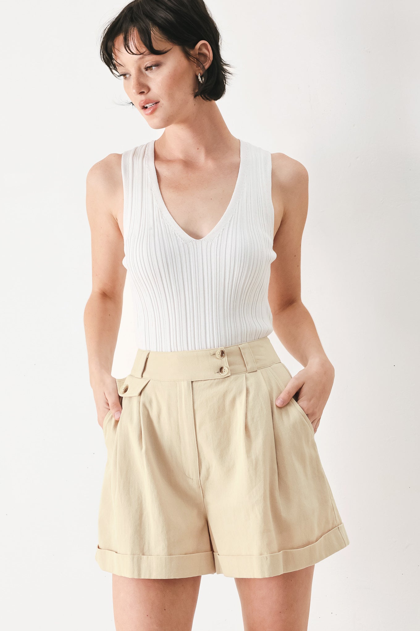 Woman wearing light beige woven shorts with front closure, pockets and cuff hem | FEEMARKET