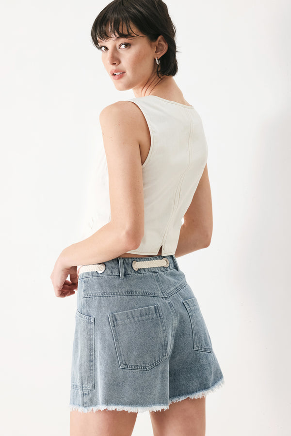 Woman wearing denim shorts with front closure, side pockets, contrasting tie with grommet and fray hem | FREEMARKET