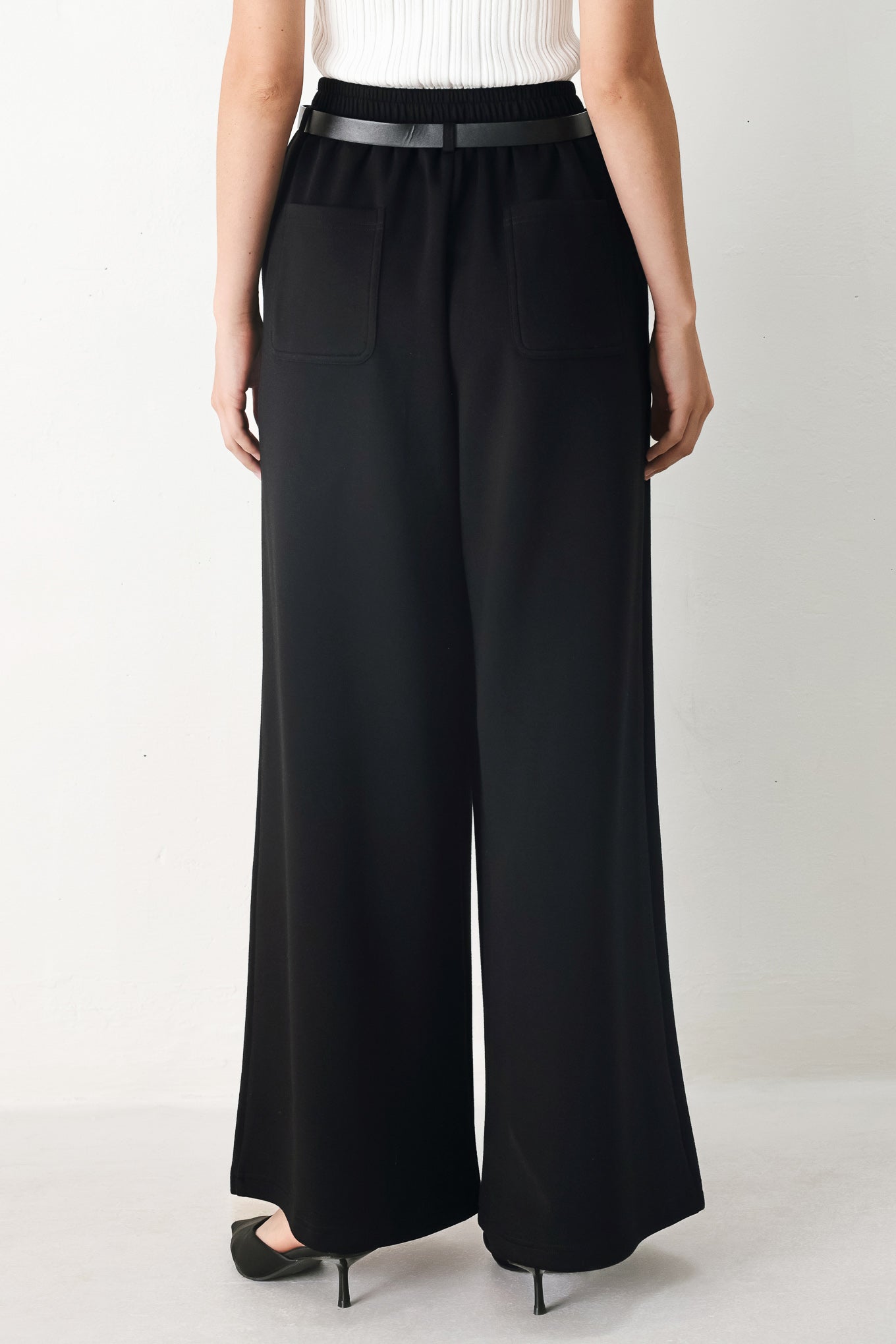 Woman wearing black wide-leg pants with a self tie belt | FREEMARKET