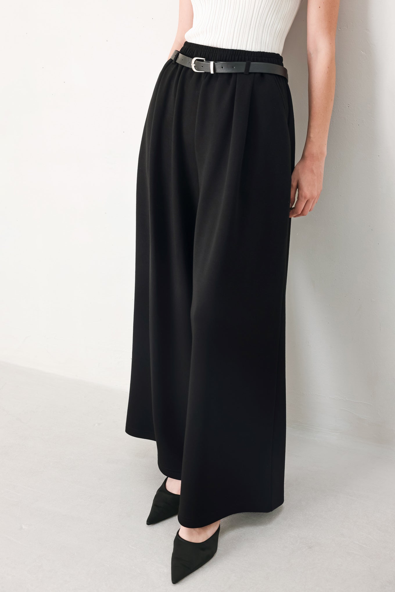 Woman wearing black wide-leg pants with a self tie belt | FREEMARKET
