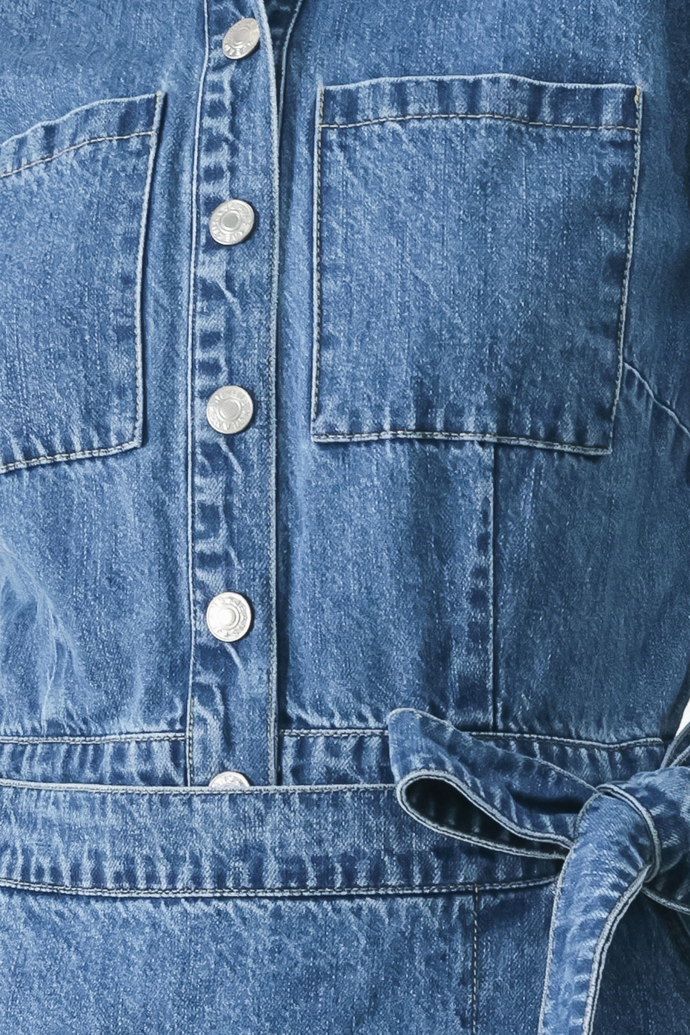 Close up of a blue denim skort romper featuring front closure, short sleeve, pockets and side tie | FREEMARKET