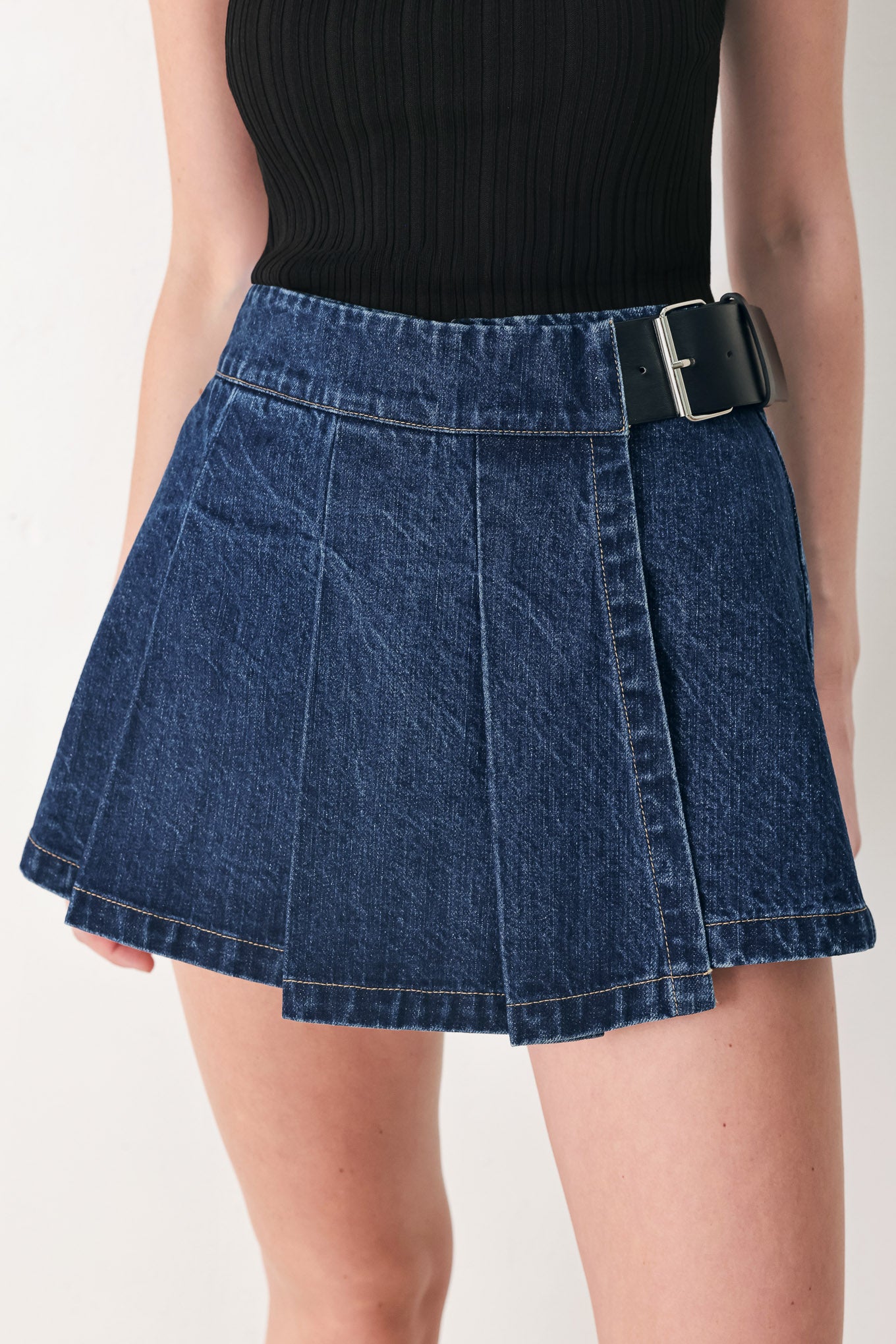 Woman wearing a blue denim skort with a black belt | FREEMARKET