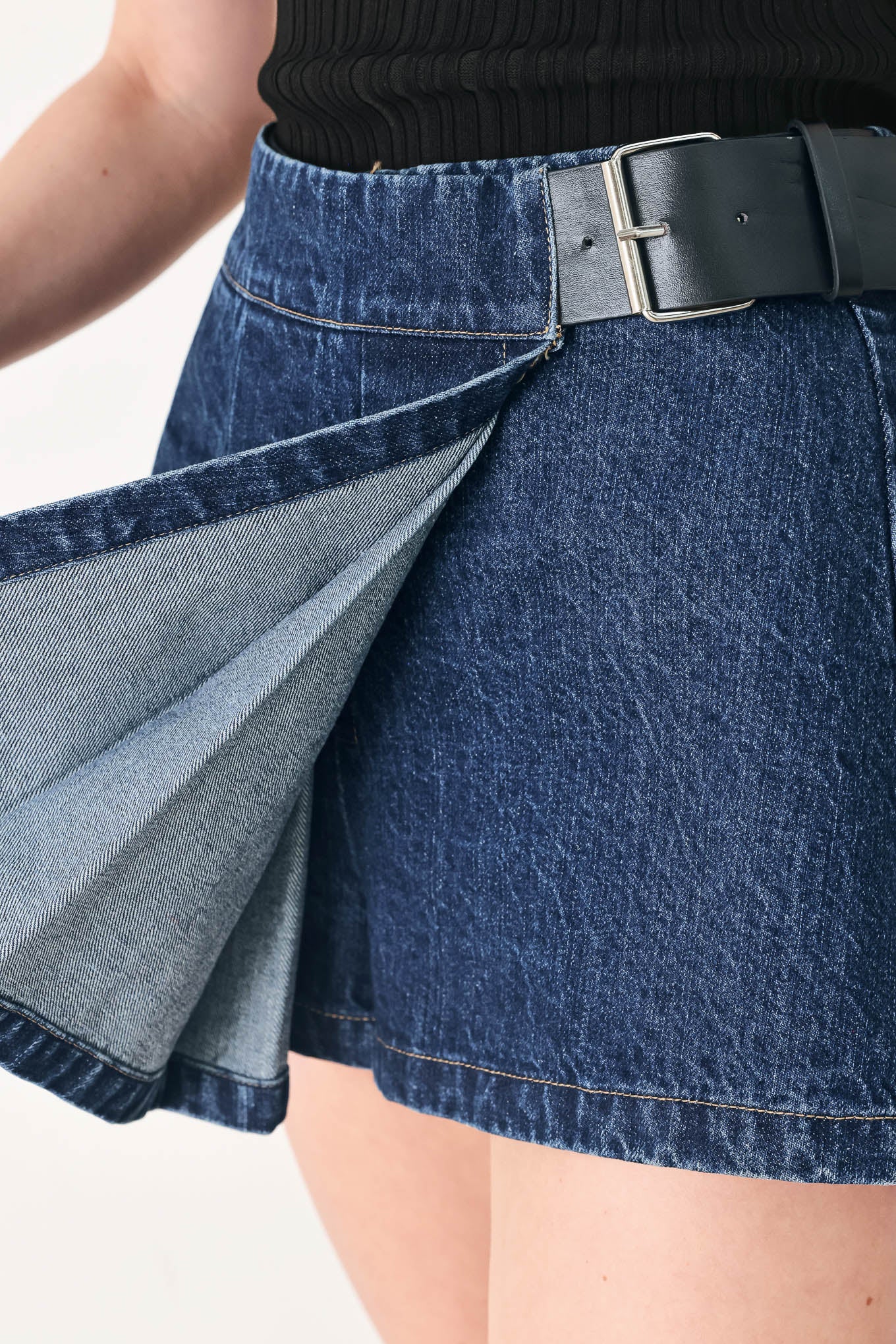 Woman wearing a blue denim skort with a black belt | FREEMARKET