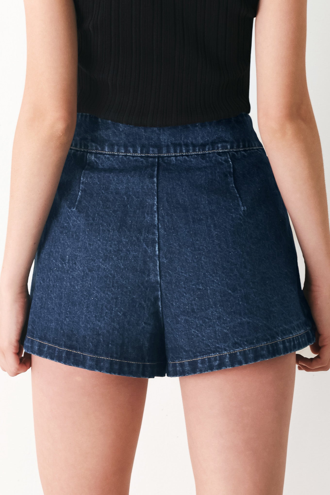 Woman wearing a blue denim skort with a black belt | FREEMARKET