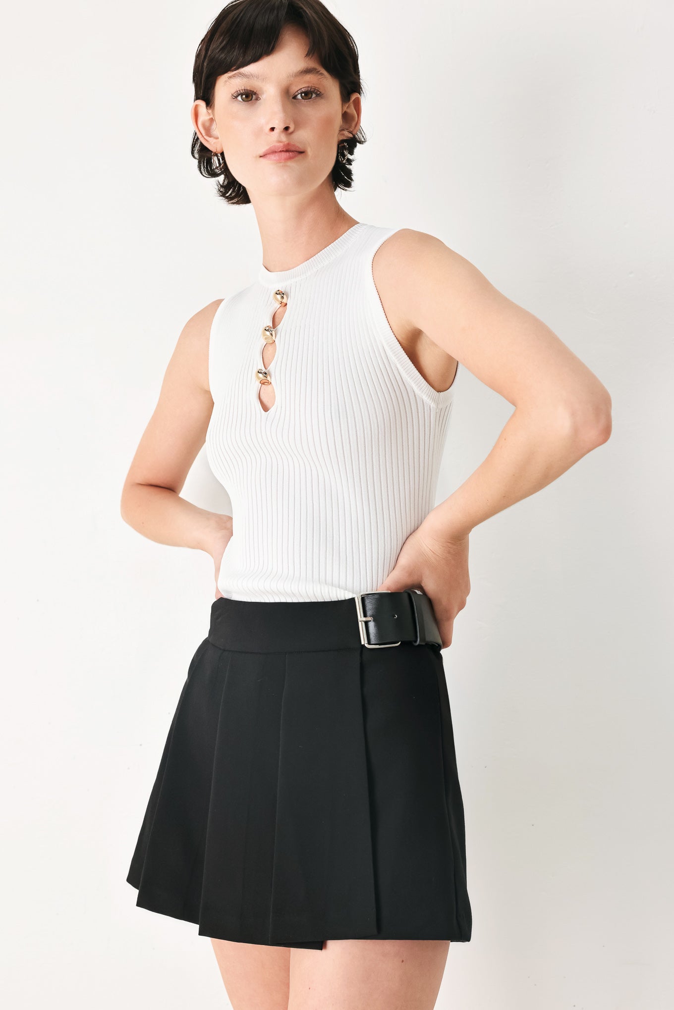 Woman wearing a black pleated skort with a belt buck off side | FREEMARKET
