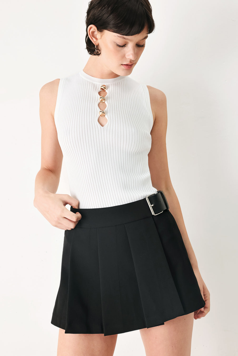 Woman wearing a black pleated skort with a belt buck off side | FREEMARKET