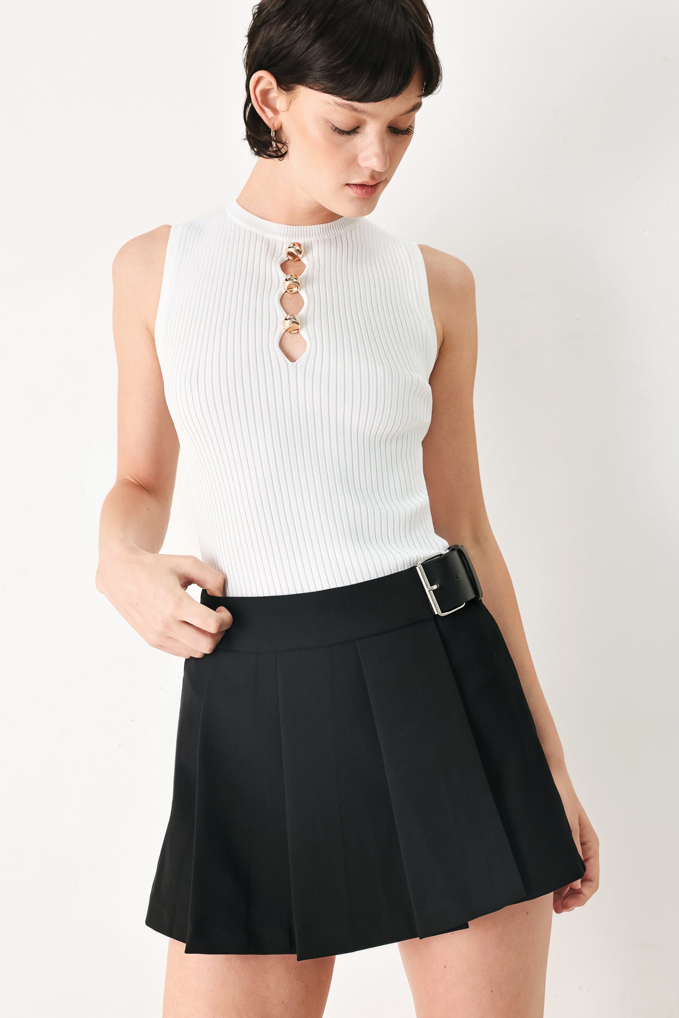 Woman wearing a black pleated skort with a belt buck off side | FREEMARKET