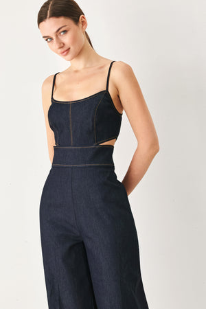 Woman wearing a dark denim jumpsuit  jumpsuit featuring U neckline, straps, side cut out, wide leg and back zipper closure | FREEMARKET