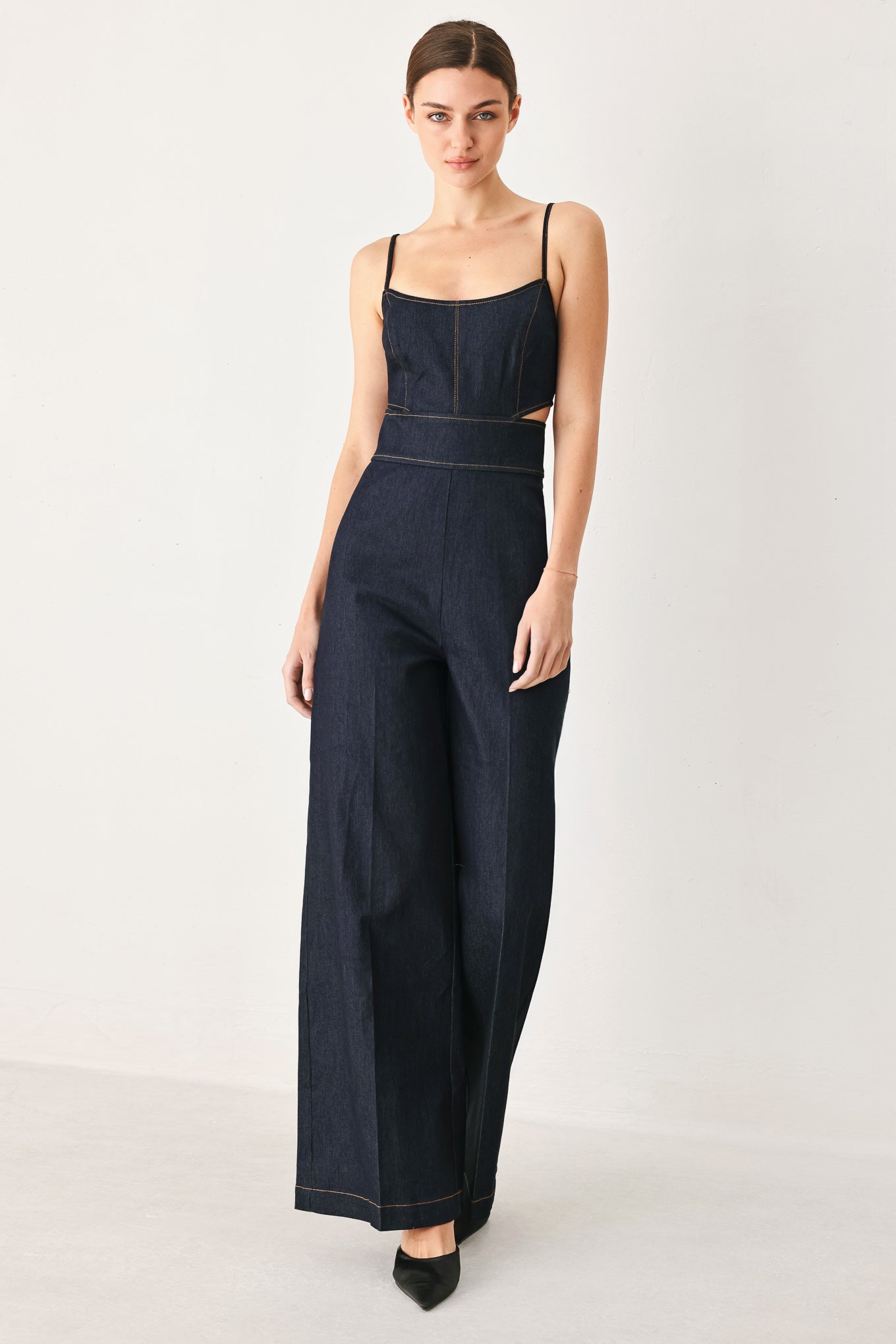 Woman wearing a dark denim jumpsuit  jumpsuit featuring U neckline, straps, side cut out, wide leg and back zipper closure | FREEMARKET
