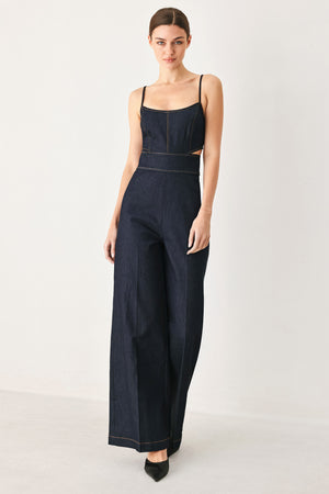Woman wearing a dark denim jumpsuit  jumpsuit featuring U neckline, straps, side cut out, wide leg and back zipper closure | FREEMARKET