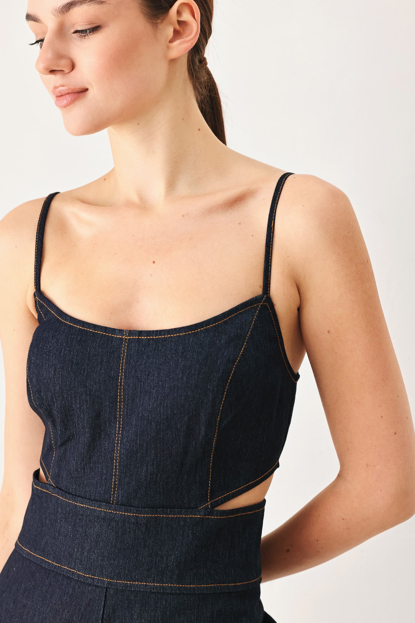 Woman wearing a dark denim jumpsuit  jumpsuit featuring U neckline, straps, side cut out, wide leg and back zipper closure | FREEMARKET