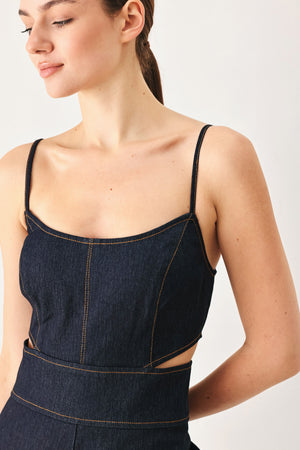 Woman wearing a dark denim jumpsuit  jumpsuit featuring U neckline, straps, side cut out, wide leg and back zipper closure | FREEMARKET