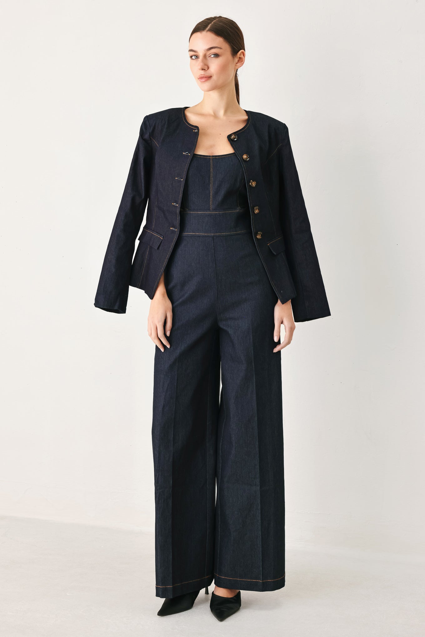 Woman wearing a dark denim jumpsuit  jumpsuit featuring U neckline, straps, side cut out, wide leg and back zipper closure | FREEMARKET