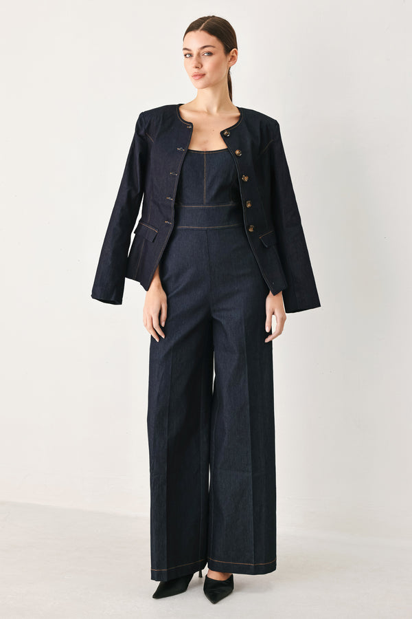 Woman wearing a dark denim jumpsuit  jumpsuit featuring U neckline, straps, side cut out, wide leg and back zipper closure | FREEMARKET