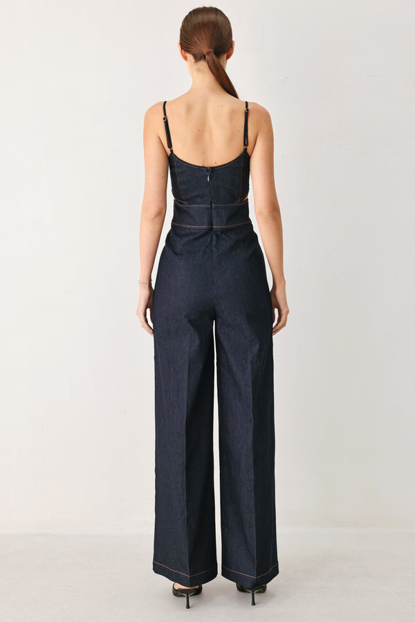Woman wearing a dark denim jumpsuit  jumpsuit featuring U neckline, straps, side cut out, wide leg and back zipper closure | FREEMARKET