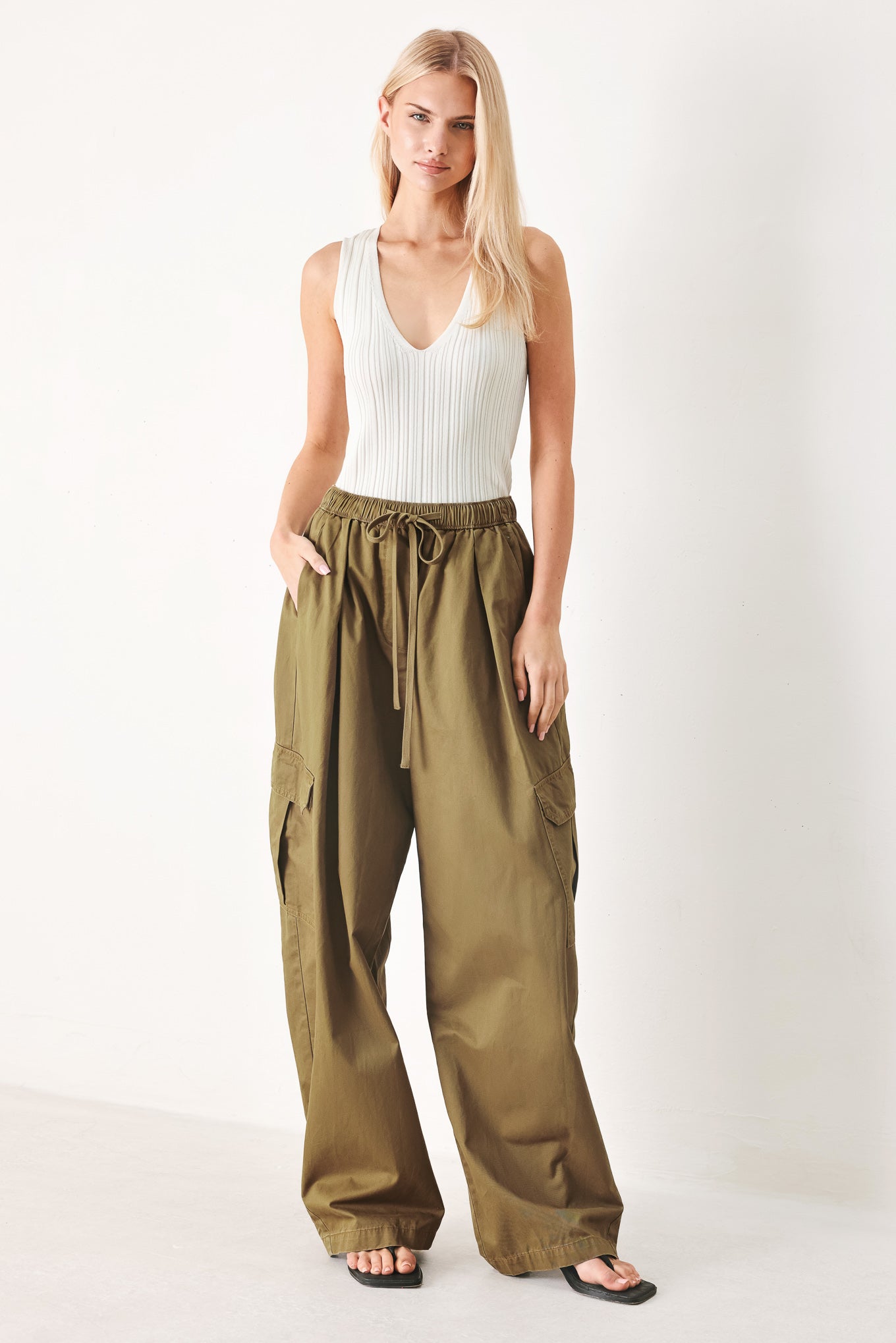 Woman wearing olive green wide-leg woven barrel pants with an elastic waist with contrasting tie and cargo pockets | FREEMARKET