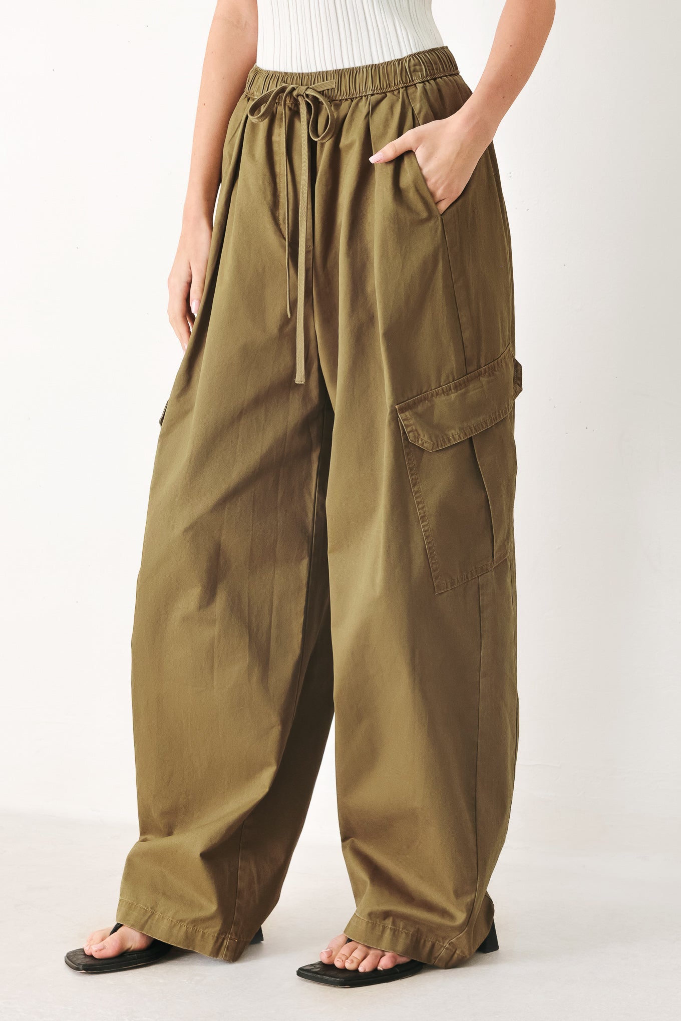 Woman wearing olive green wide-leg woven barrel pants with an elastic waist with contrasting tie and cargo pockets | FREEMARKET