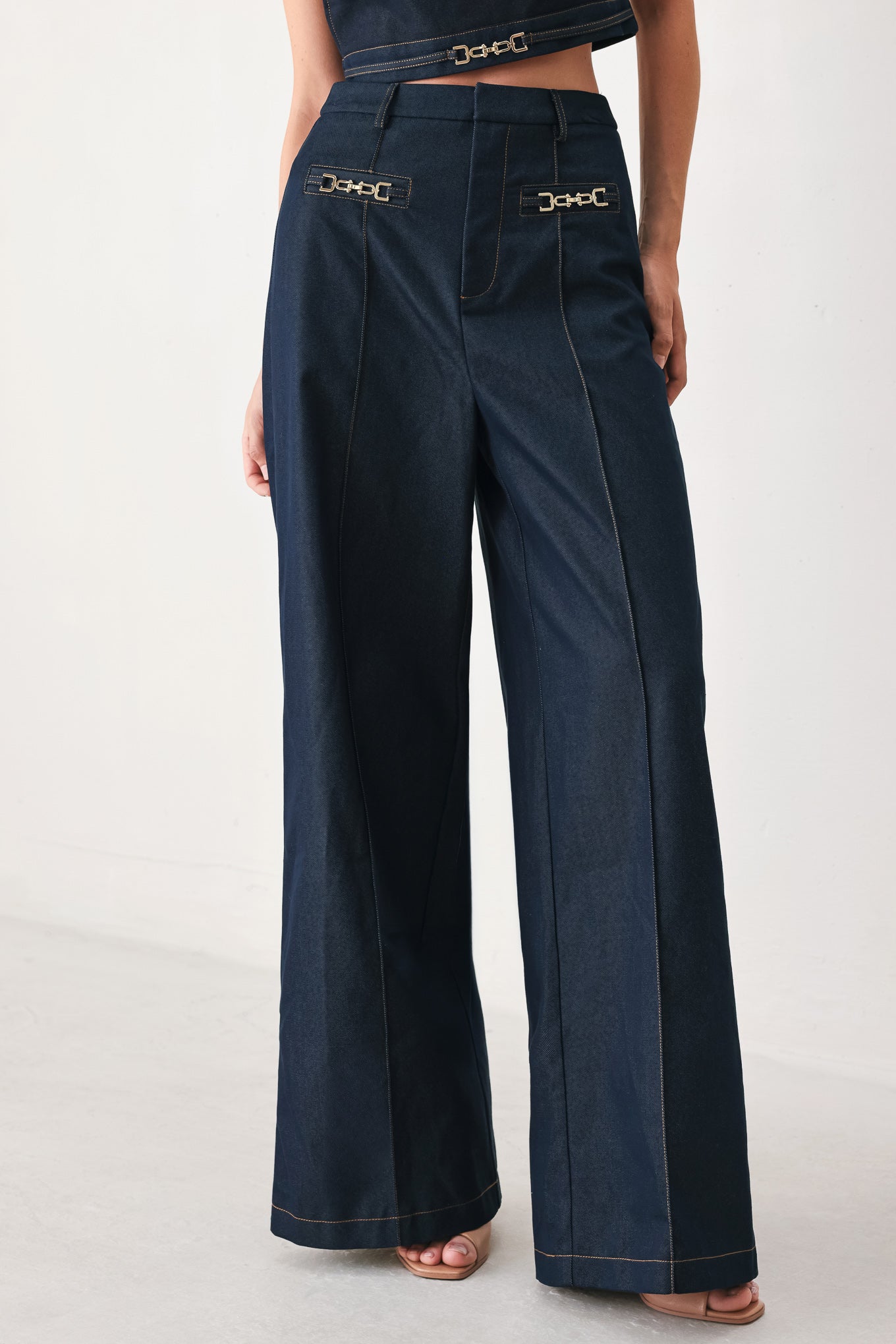 Woman wearing navy blue wide-leg pants with gold belt details | FREEMARKET