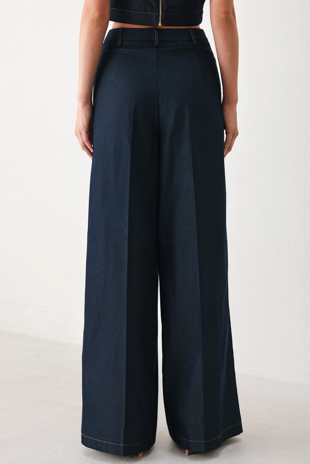 Woman wearing navy blue wide-leg pants with gold belt details | FREEMARKET