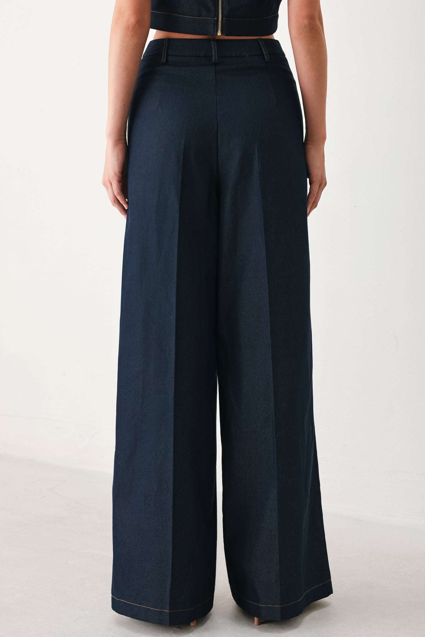 Woman wearing navy blue wide-leg pants with gold belt details | FREEMARKET