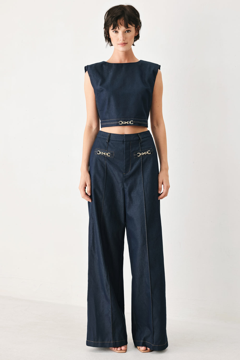 Woman wearing navy blue wide-leg pants with gold belt details | FREEMARKET
