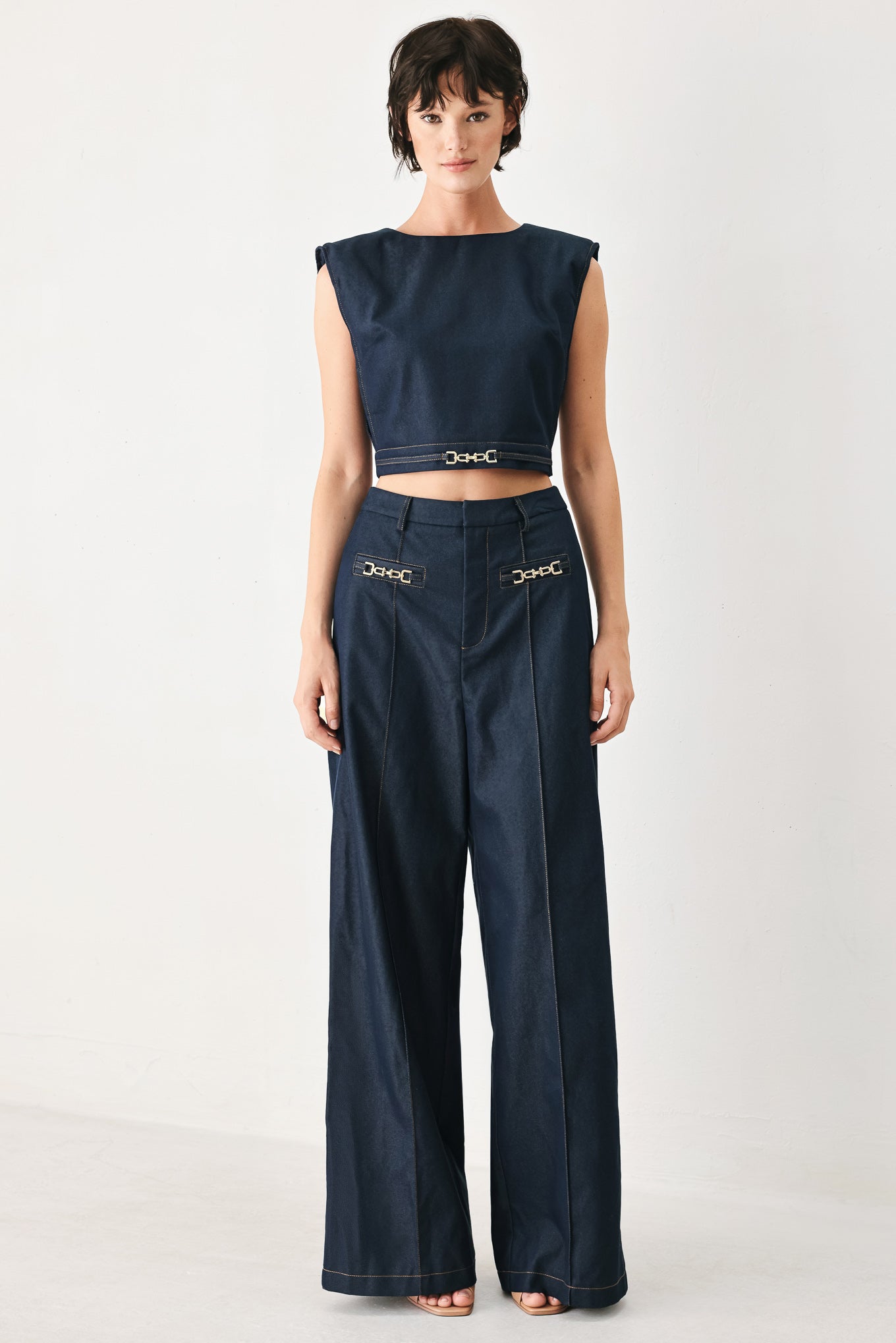 Woman wearing navy blue wide-leg pants with gold belt details | FREEMARKET
