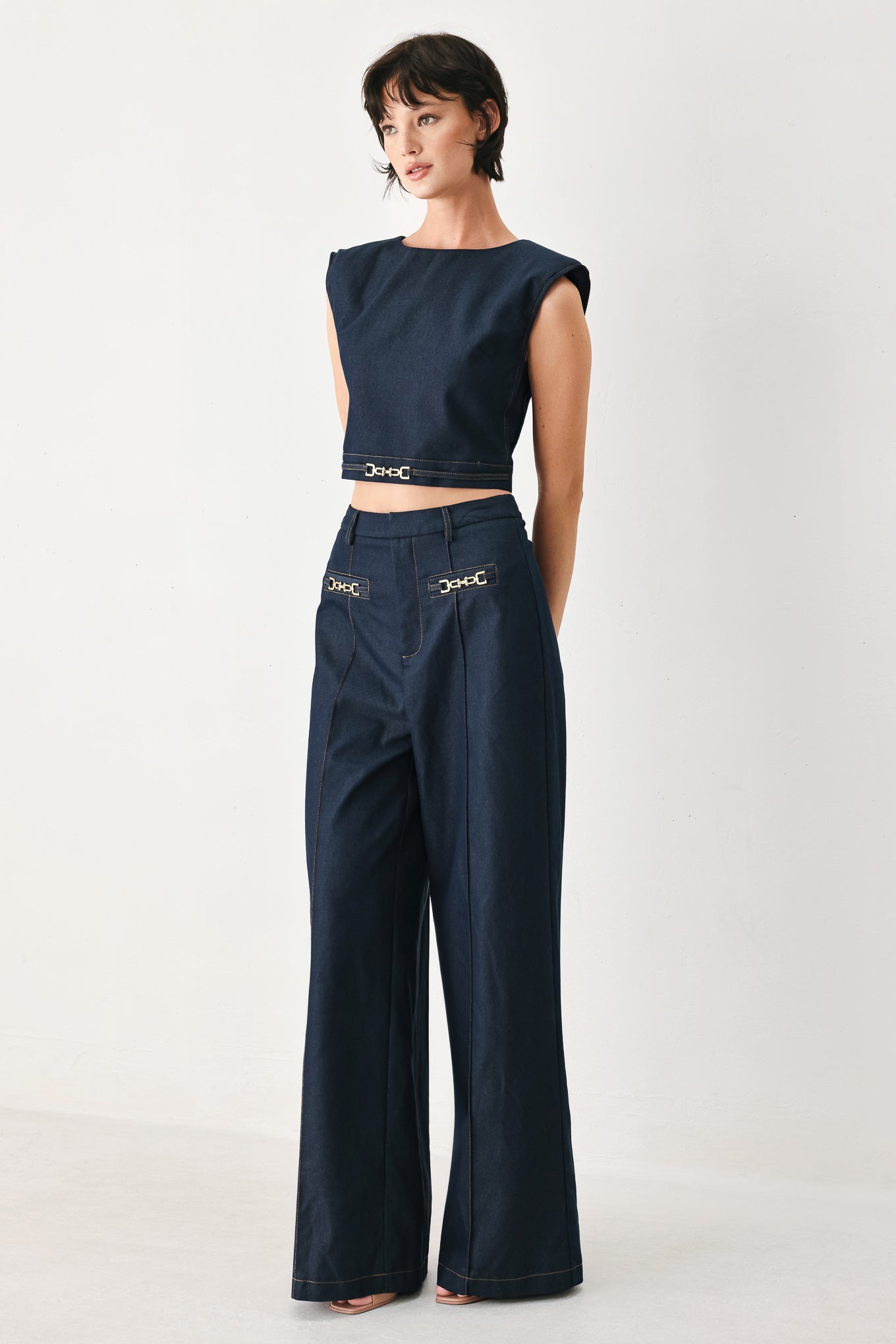 Woman wearing navy blue wide-leg pants with gold belt details | FREEMARKET