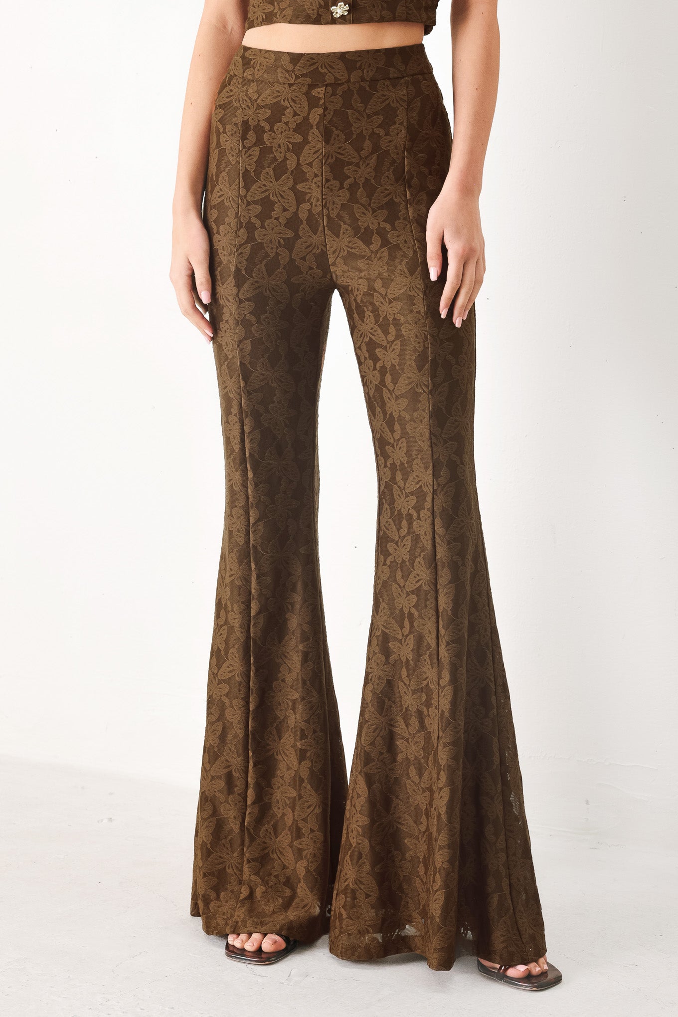 Woman wearing brown patterned bell-bottom pants with flare leg and back zipper closure | FREEMARKET