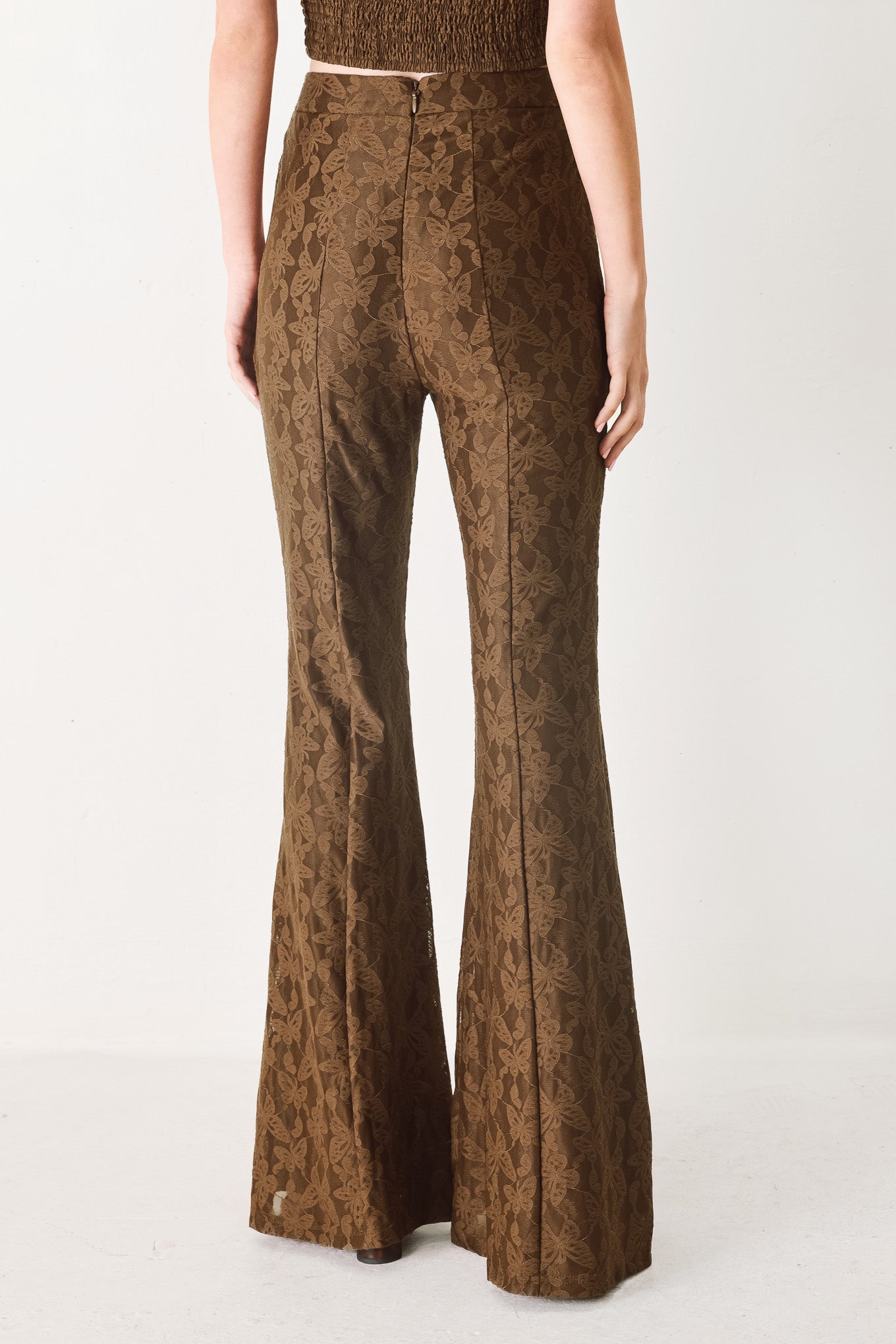 Woman wearing brown patterned bell-bottom pants with flare leg and back zipper closure | FREEMARKET