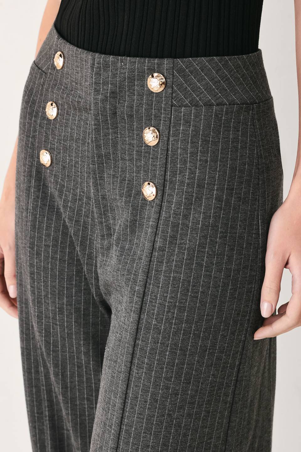Woman wearing high-waisted, wide-leg charcoal gray and white pinstriped trousers with decorative gold-tone buttons on the front waistband | FREEMARKET