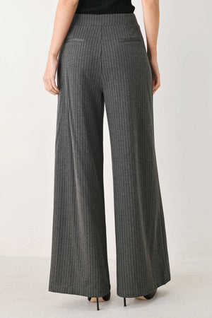 Woman wearing high-waisted, wide-leg charcoal gray and white pinstriped trousers with decorative gold-tone buttons on the front waistband | FREEMARKET