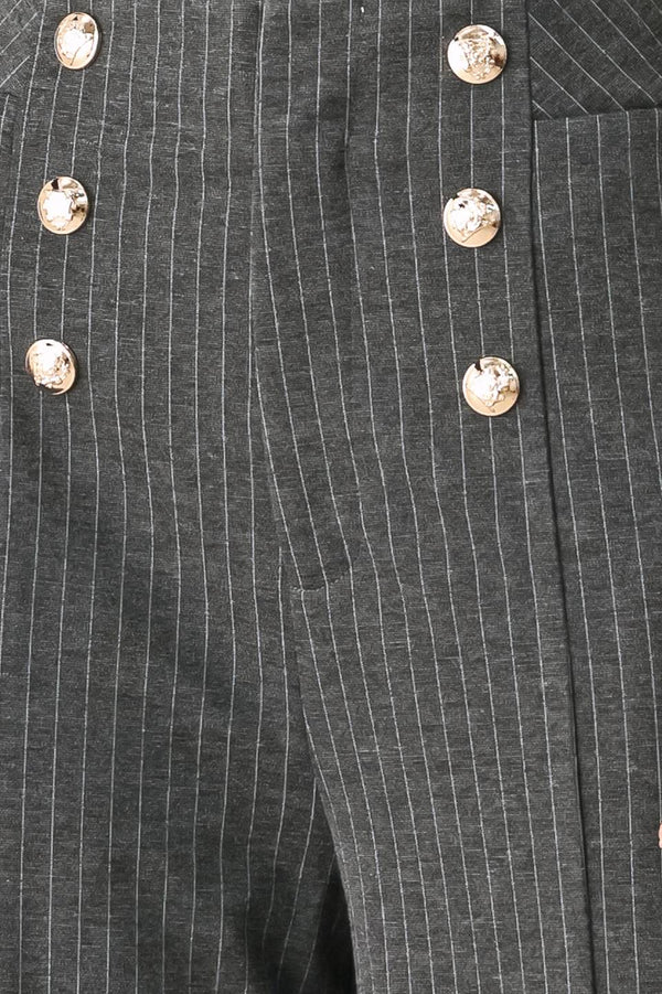 Woman wearing high-waisted, wide-leg charcoal gray and white pinstriped trousers with decorative gold-tone buttons on the front waistband | FREEMARKET