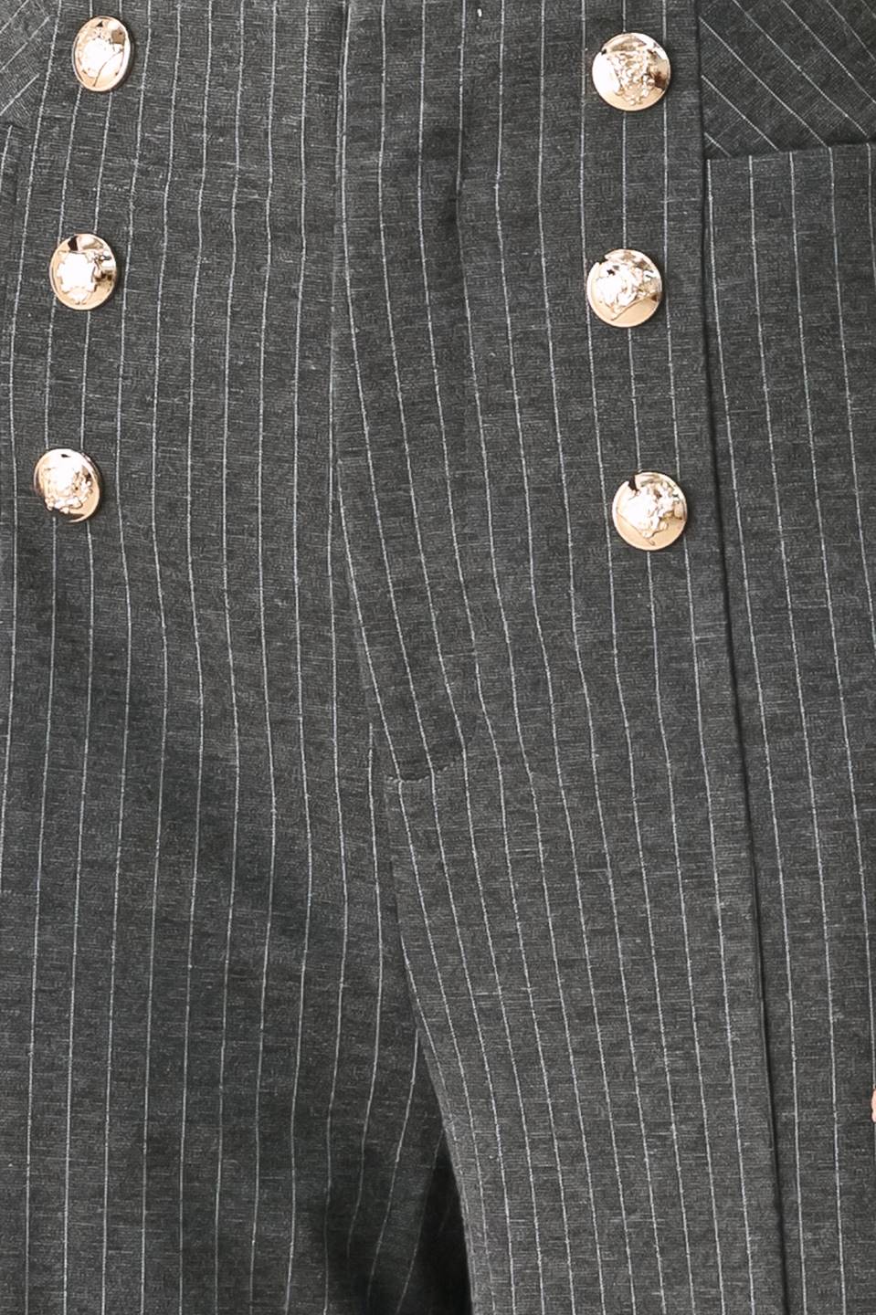 Woman wearing high-waisted, wide-leg charcoal gray and white pinstriped trousers with decorative gold-tone buttons on the front waistband | FREEMARKET