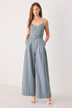 A woman wearing a sleeveless wide-leg jumpsuit with vertical blue, beige, and white stripes, featuring a V-neck bodice, thin shoulder straps, and a matching fabric belt with a silver buckle | FREEMARKET