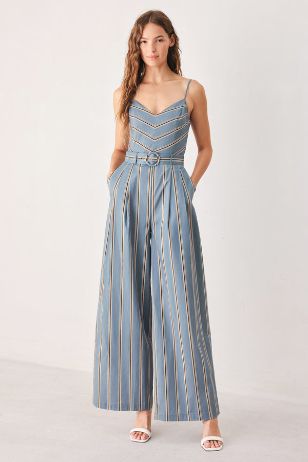 A woman wearing a sleeveless wide-leg jumpsuit with vertical blue, beige, and white stripes, featuring a V-neck bodice, thin shoulder straps, and a matching fabric belt with a silver buckle | FREEMARKET