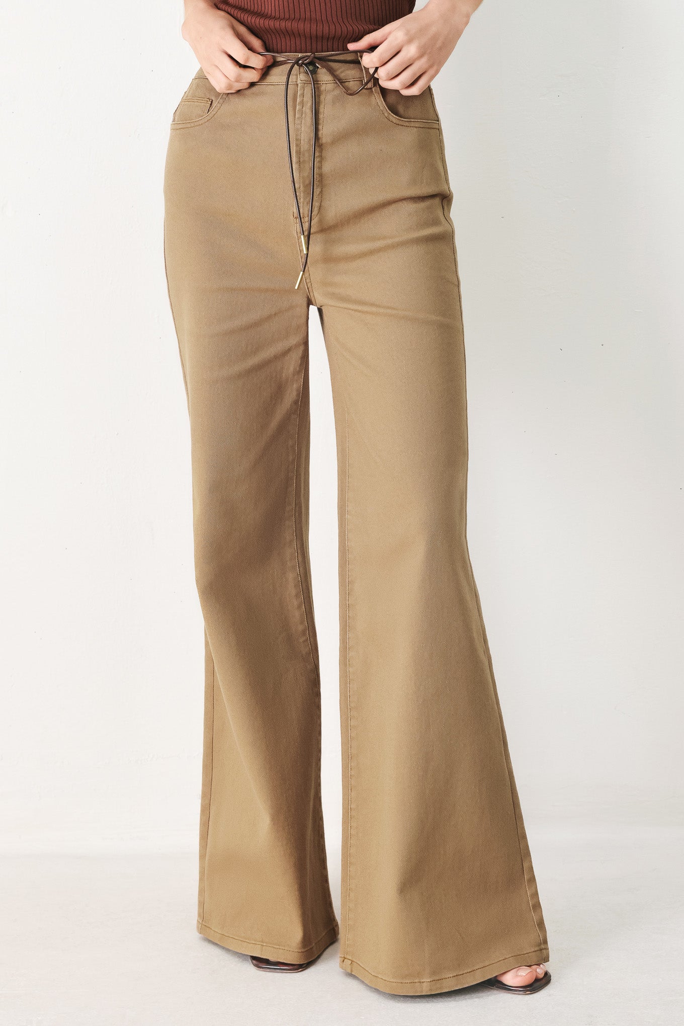 Woman wearing khaki wide-leg pants with front closure and contrasting belt | FREEMARKET