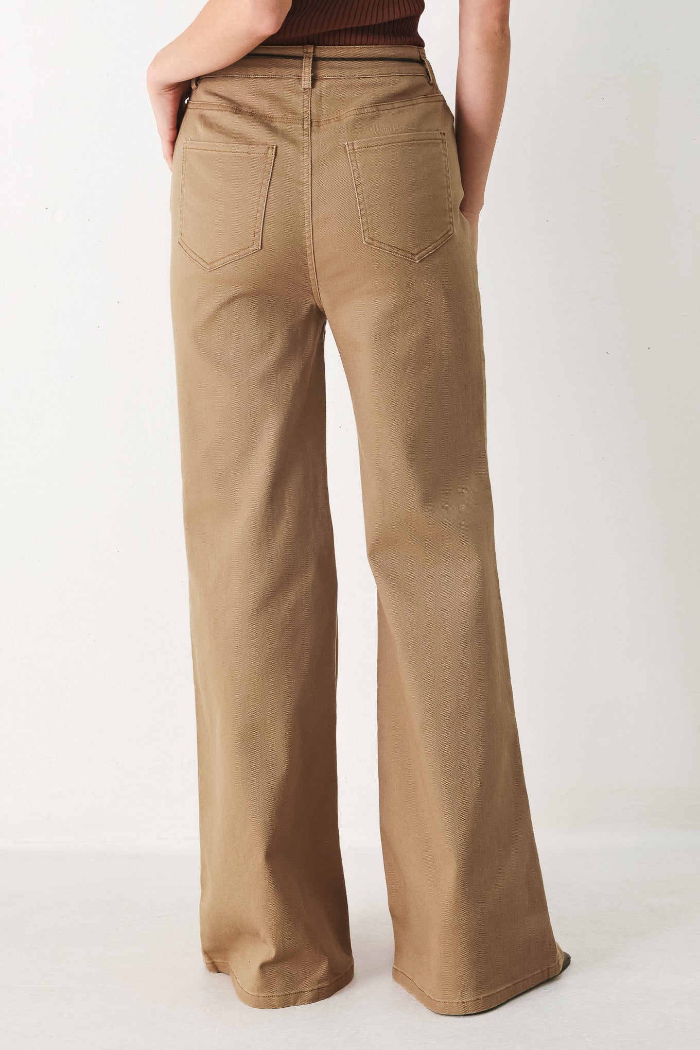 Woman wearing khaki wide-leg pants with front closure and contrasting belt | FREEMARKET