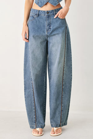 Woman wearing light blue denim balloon pant with front closure, pockets and piping detail | FREEMARKET