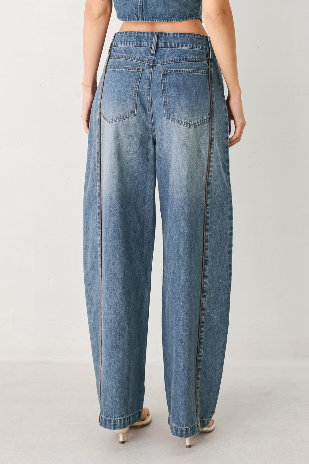 Woman wearing light blue denim balloon pant with front closure, pockets and piping detail | FREEMARKET