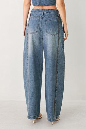 Woman wearing light blue denim balloon pant with front closure, pockets and piping detail | FREEMARKET